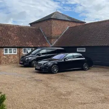 two-chauffeur- service-cars-parked Two black cars outside of building